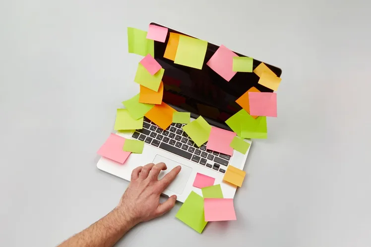 Laptop covered in sticky notes, overwhelmed with tasks